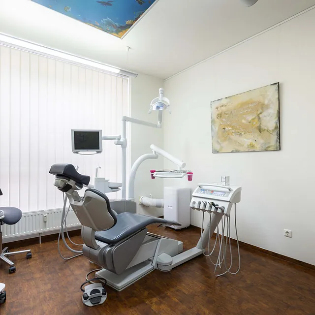 Modern ausgestattetes zahnärztliches Behandlungszimmer mit Zahnarztstuhl, Behandlungseinheit und medizinischen Geräten in der Zahnarztpraxis am Stadtpark in Lübeck.