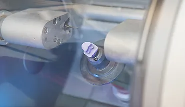 Dentale Fräsmaschine bei der computergestützten Herstellung von keramischem Zahnersatz. Moderne CEREC-Technologie für Zahnkronen und Zahnersatz in Lübeck.